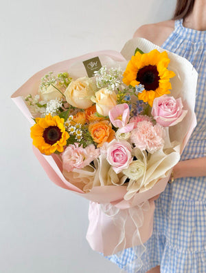 A girl in a blue dress holds a sunflower bouquet, celebrating her university graduation day in Kuala Lumpur.