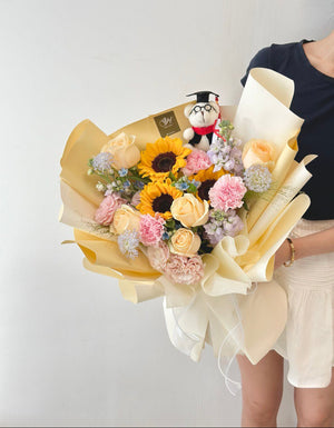 A graduate in Kuala Lumpur proudly holds a large size sunflower bouquet and a stuffed bear on her graduation day.