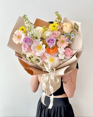 A girl in a black dress presents a birthday bouquet of tulips and mixed roses, prepared for her celebration.