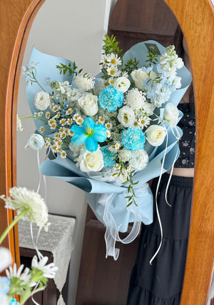 A person is holding a bouquet of blue flower facing a wooden frame mirror for picture.