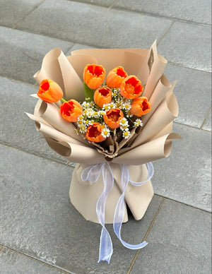 In Kuala Lumpur, a bouquet of orange tulip is placing on grey tile for photoshoot.