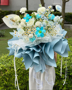 Elegant blue and white flower bouquet featuring roses, dye tulip, and anthurium wrapped in pastel blue paper.