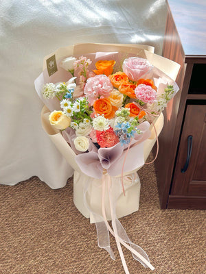 A fresh spring-inspired bouquet with orange and blush tones, accented by hana white, eustoma, oxypetalum blue and matthiola.