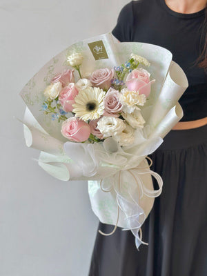 A woman dressed in black holds a colorful bouquet of flowers, captured in a photo.