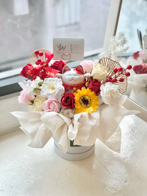 A white box with a floral bouquet and a lucky cat on top, marking a business opening event in Kuala Lumpur.