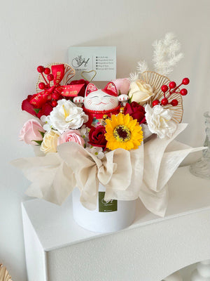 A white box with a bouquet of flowers and a lucky cat on top, celebrating a business opening in Kuala Lumpur.