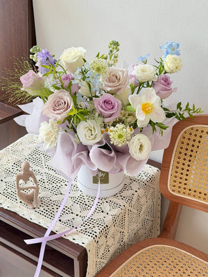 Bouquet of flowers on a table with a chair and lace tablecloth in the background
