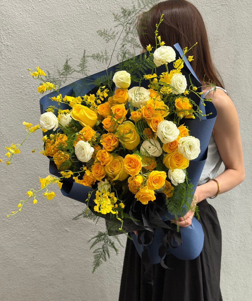 Person holding a large bouquet of yellow and white eustoma against a plain background at Hug and Heart Florist.