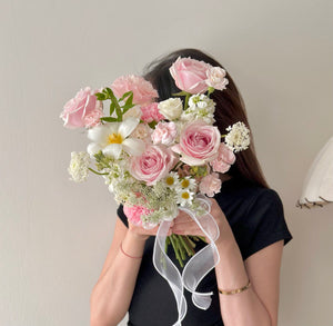 Close-up of a romantic pastel bridal bouquet featuring roses, hana white, and lace-like blooms.