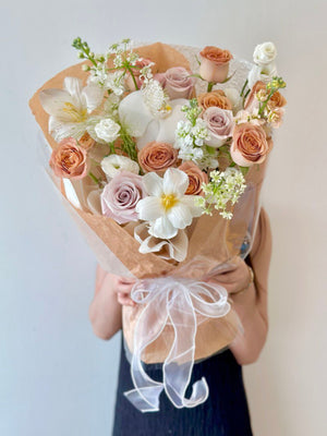 A woman in a black dress holds a large bouquet of cappuccino roses for her birthday in Kuala Lumpur.