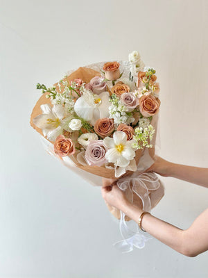 A girl in a black dress presents a large bouquet of cappuccino roses at her birthday celebration in Kuala Lumpur.