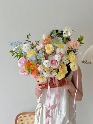Person holding a bouquet of flowers in a basket with a plain background perfect for get well soon gift.