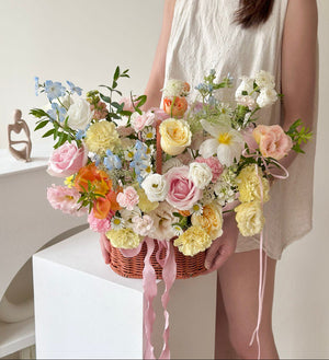 Person holding a basket of colorful flowers with a white background