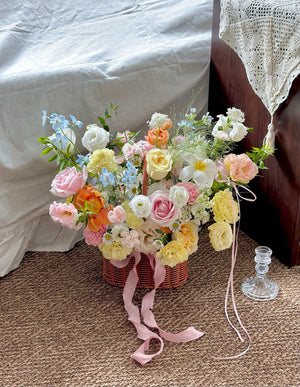 Bouquet of flowers in a basket with ribbons on a textured surface.
