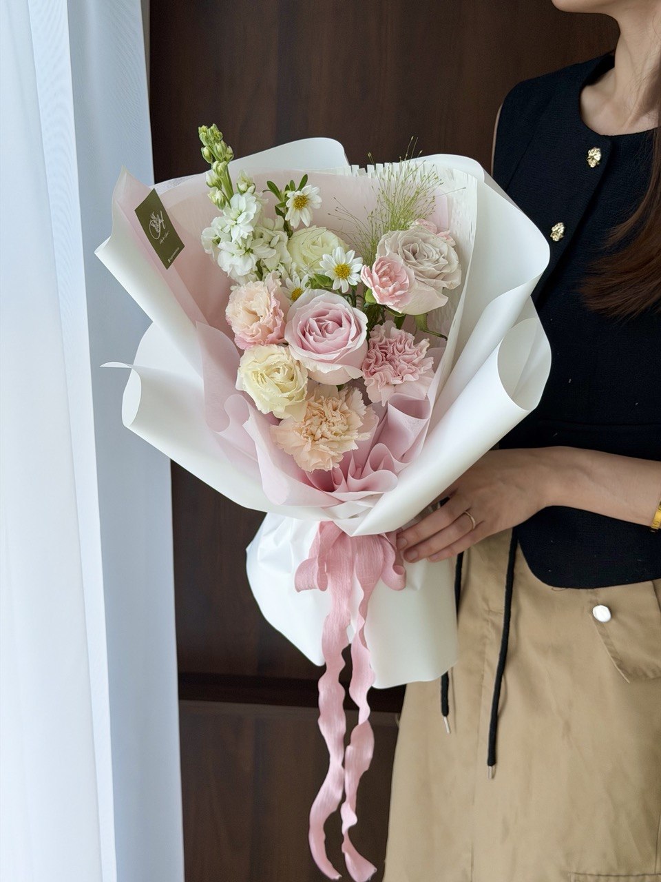 A girl wearing black top is holding a bouquet of pink roses with mixed filler perfect for birthday flower and same day flower delivery at Kuala Lumpur and Selangor.