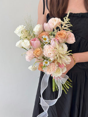 Elegant ROM bouquet in soft pastel shades of peach, pink, and ivory with astilbe and pink tulip.