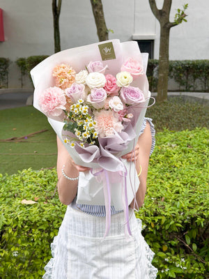 Person holding a bouquet of flowers outdoors with greenery in the background, with same day delivery at Sunway Square.