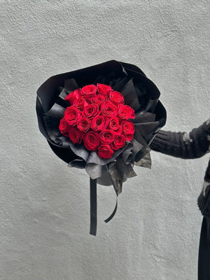 20 red roses flower bouquet is holding by a hand in a grey background in malaysia.