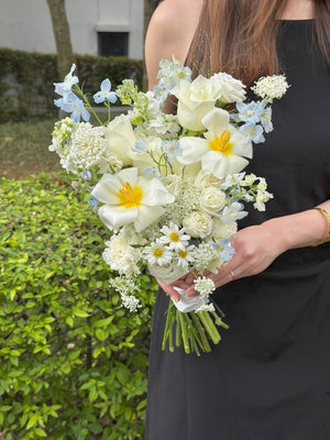 Fresh garden-style wedding bouquet with white tulips, ivory roses, blue delphinium and soft blue oxypetalum, available for same day flower delivery across Kuala Lumpur and Selangor.