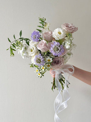 Handheld bridal bouquet with Menta roses and purple scabiosa in soft lavender and white tones.