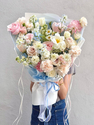 Elegant pastel blue and pink bouquet with pink roses, blue delphinium, white tulip, carnations, chamomile, and fresh fillers, beautifully hand-tied for same-day flower delivery across KL and Selangor.