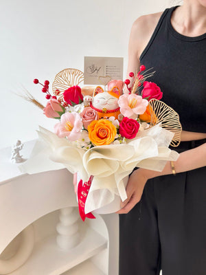 Decorative grand opening gift with a ceramic lucky cat and a mix of colorful flowers, including roses and cherry blossoms, arranged in a white base with modern decor.
