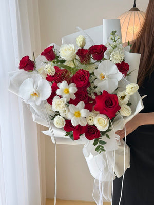 A large birthday bouquet of red rose and white rose is held by a girl against a white wall at Subang Jaya.