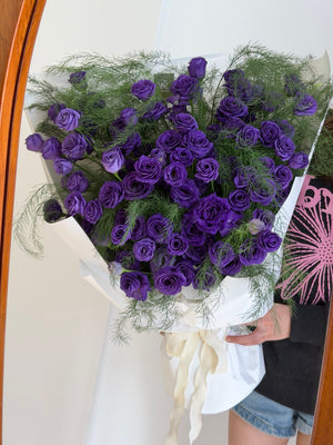 Bouquet of purple eustoma flowers held by a person against a white background at Hug and Heart Florist Subang Jaya Selangor.