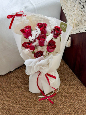 Bouquet of red roses wrapped in white paper with a red ribbon perfect for Christmas present.