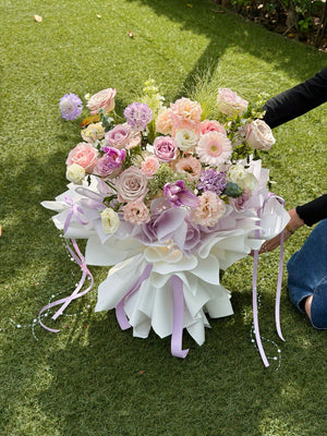 Luxury pastel purple theme floral bouquet featuring lilac roses, pink gerbera, peach carnations and seasonal fillers, perfect for birthday or anniversary gift.