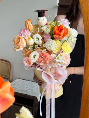 Bouquet of flowers with a graduation ping pong with a cap held by a person in front of a mirror.