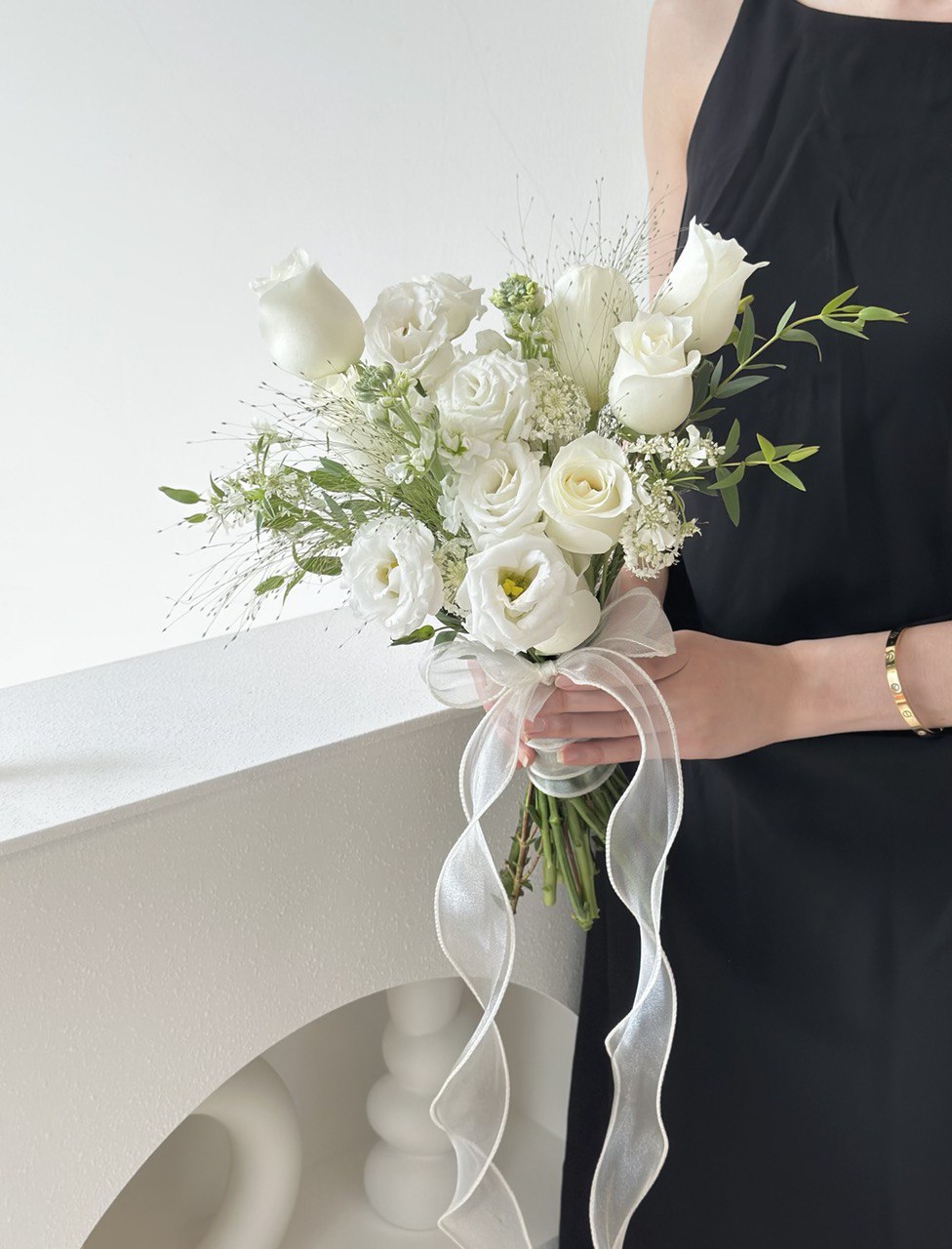 Minimalist floral arrangement in soft white tones, held by someone in a black outfit—perfect for weddings or ROM