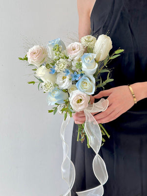 Romantic white and light blue flower arrangement for ROM, held in front of a white wall.
