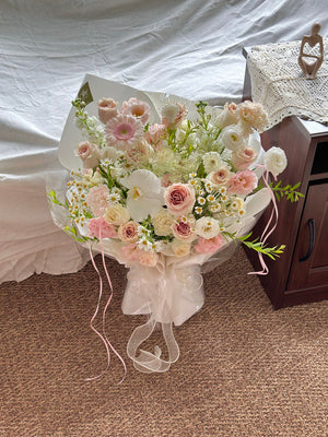 Stylish modern flower bouquet with Quicksand roses and soft blush tones place on a carpeted floor.