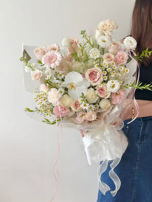 Elegant Quicksand rose bouquet with pastel flowers wrapped in white paper.