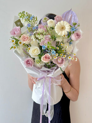 Romantic anniversary bouquet with pastel blooms, including lilac and white roses, white gerbera daisy, and blue oxypetalum blue, symbolizing timeless love.