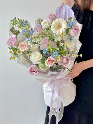 A soft and elegant pastel bouquet featuring lilac and white roses, gerbera, and delicate mixed flowers, perfect for a graceful birthday celebration.