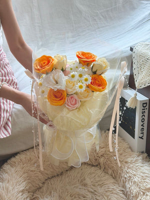 Beautiful soap flower bouquet with orange roses and white blooms in round wrap, suitable for birthday and anniversary gifts.