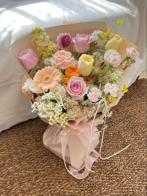 Romantic floral arrangement with roses, carnations, chamomile, and delicate filler flowers in pastel shades.