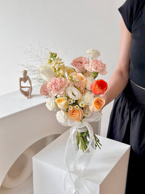 A woman in a black dress holds a vibrant bridal bouquet of orange tulips and assorted roses, exuding charm and grace.