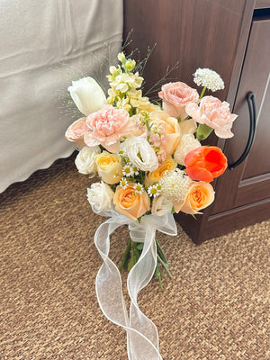 A girl wearing a black dress holds a lovely bouquet of orange tulips and a variety of roses, perfect for a bridal occasion.