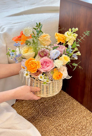 A lovely flower basket is holding by a hand, an ideal gift for housewarming or to wish someone a speedy recovery.