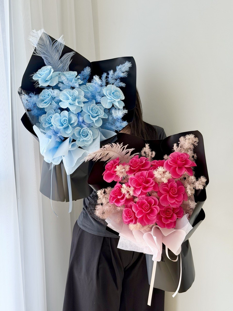 A girl wearing black is holding blue soap flower rose bouquet and hot pink soap flower bouquet with preserved-style roses, perfect for birthdays, anniversaries, and same day flower delivery by Hug and Heart Florist Sunway Geo.