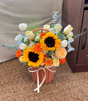 A basket of flower with sunflower, buttercup rose, delphinium blue, eustoma, orange rose spray suitable for get well soon, speedy recovery, business opening occassion.
