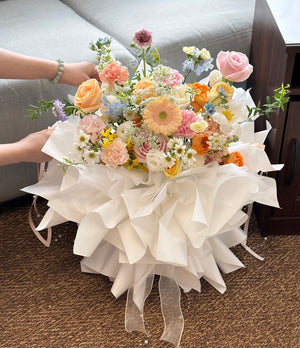 Bouquet of flowers with white ribbons held by a person on a carpeted floor ideal as a romantic anniversary surprise.