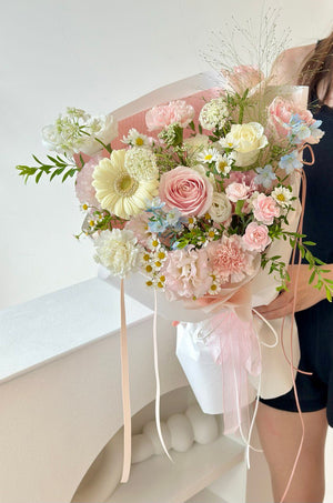 Bouquet of flowers with pink and white tones held by a person against a white background