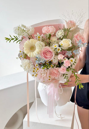 A charming floral bouquet with gentle pastel tones and lush textures, ideal for expressing love and appreciation held by a person against a white background.