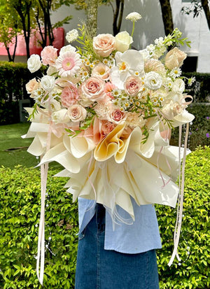 A girl with blue top is holding a flower bouquet with quicksand rose suitable for birthday and anniversary gift idea.