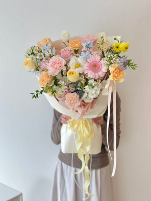 Bouquet of colorful flowers held by a person against a plain background