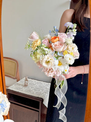 Bouquet of wedding flowers held by a person in a room with a mirror and table.